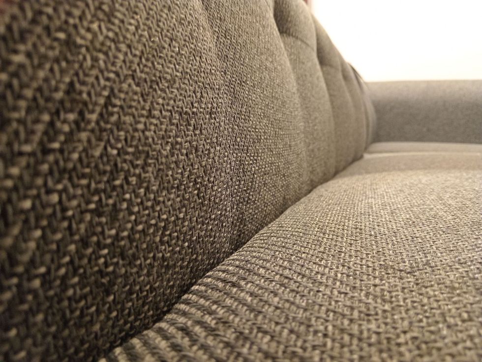 Close-up of brown tufted leather upholstery with diamond stitching and brass buttons