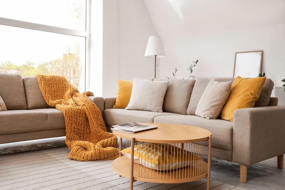 Modern open-plan living room with white sofa, wooden dining table, and blue chairs