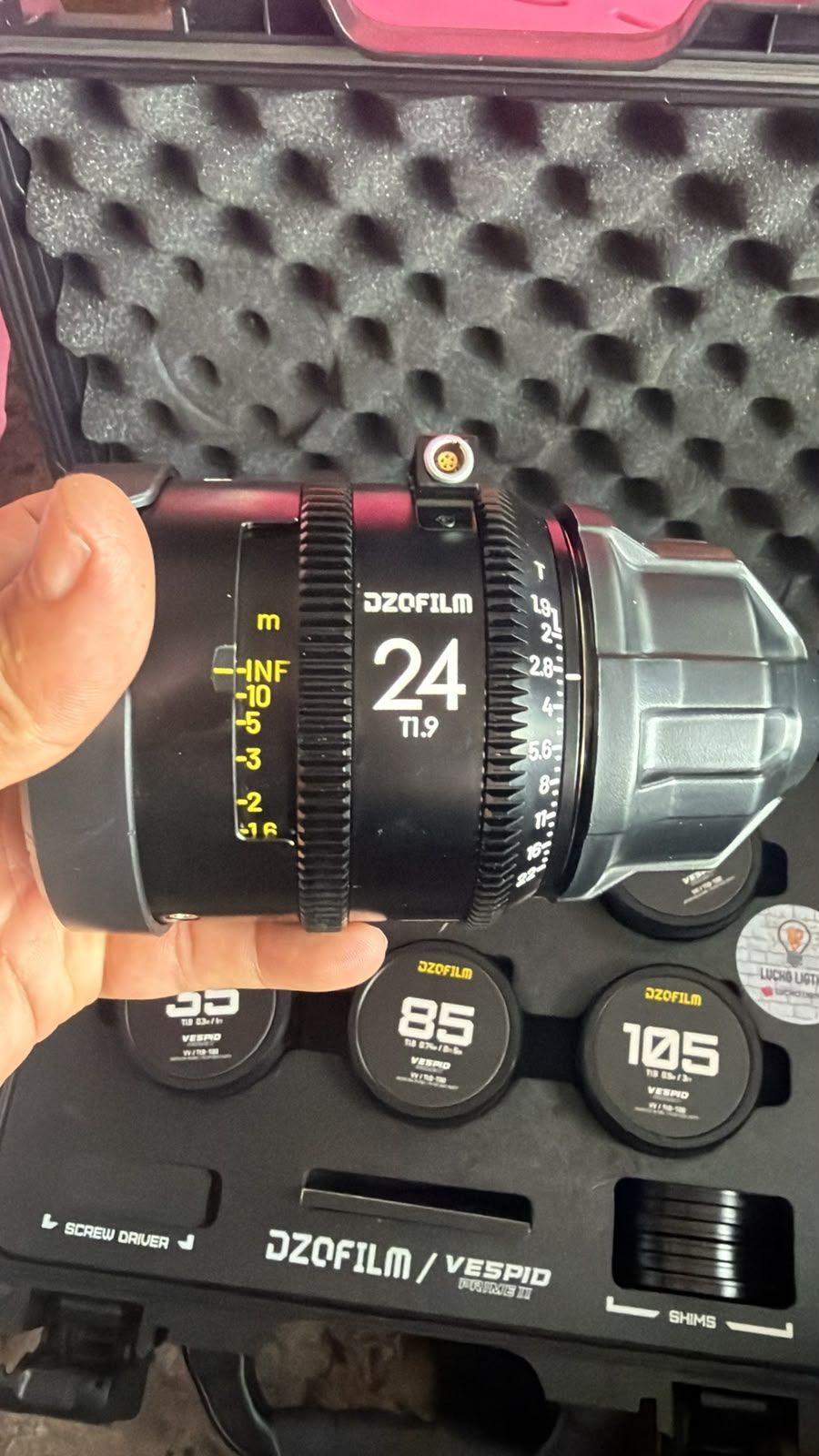 Objetivo ZOMEI de 24 mm para cámara, portátil, en un estuche negro forrado de espuma.