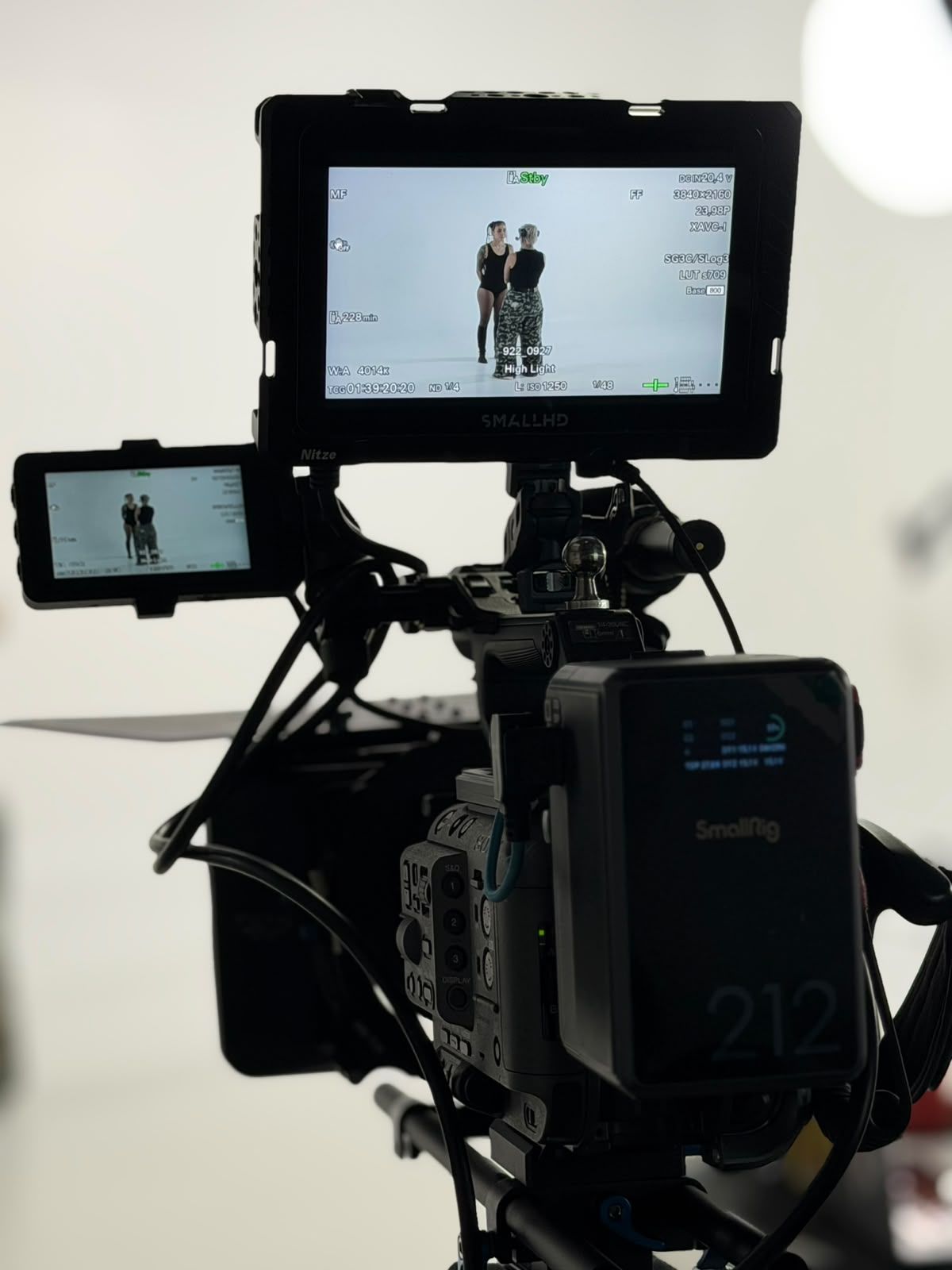 Equipo de cámara con dos monitores, grabando a dos personas frente a un fondo blanco