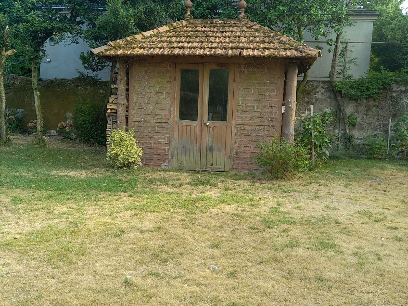 Jardin à Nantes avant les travaux : cabane en briques et pelouse brûlée par la sécheresse