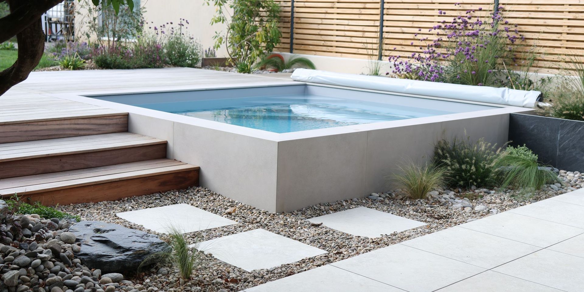Mini-piscine surélevée habillée de céramique effet béton ciré dans un jardin à Basse-Goulaine