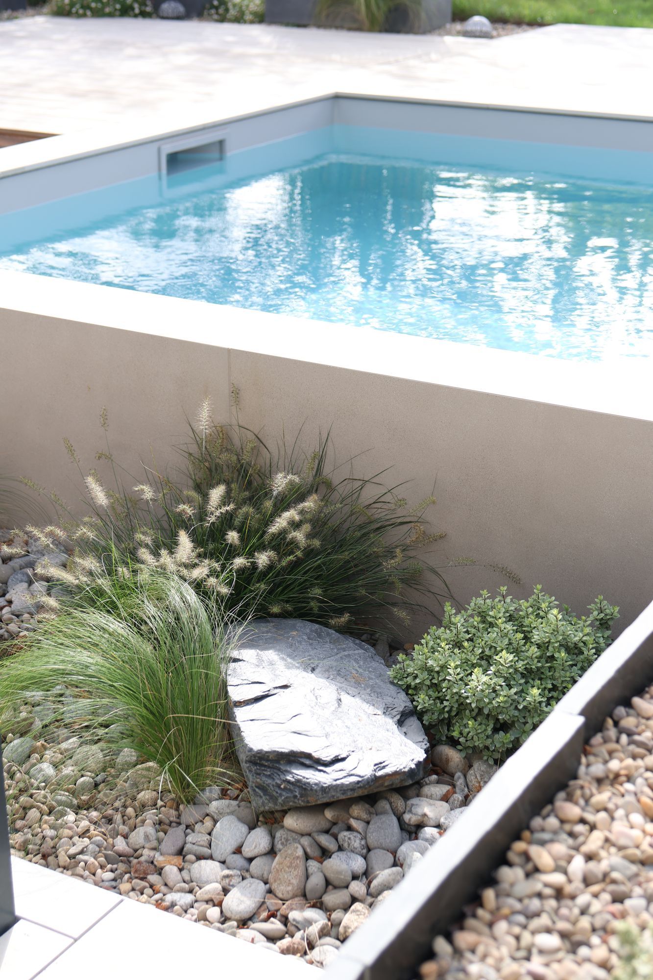 Mini-piscine surélevée en céramique et paillage de galets dans un jardin à Basse-Goulaine