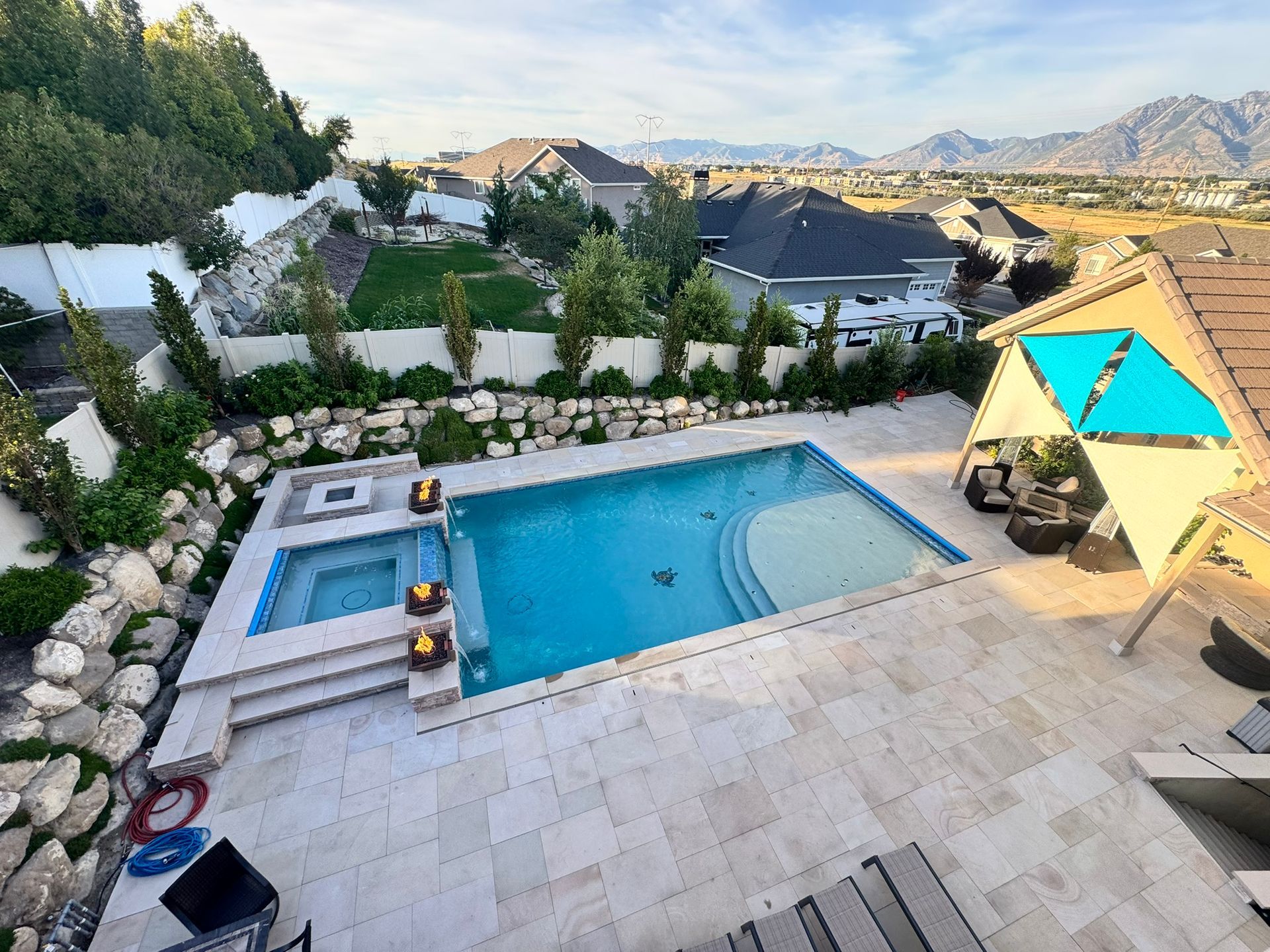 An empty, rectangular backyard swimming pool under construction with dark stone coping and a light plaster finish.