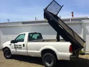 White pickup truck with a raised black dump bed.