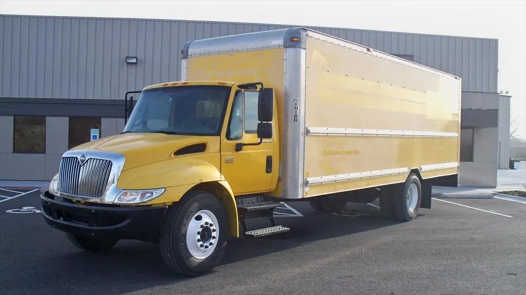 Yellow box truck parked in front of a building.