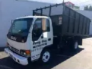 White Isuzu truck with a dark green dumpster bed parked outdoors.