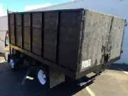 Black dump truck with white wheels, parked in front of a building.