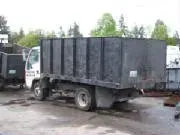 Black dump truck parked outside; trees in the background.