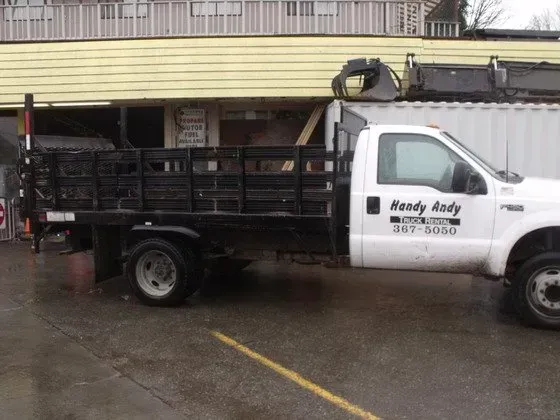 White work truck parked next to a building. The truck bed is black.