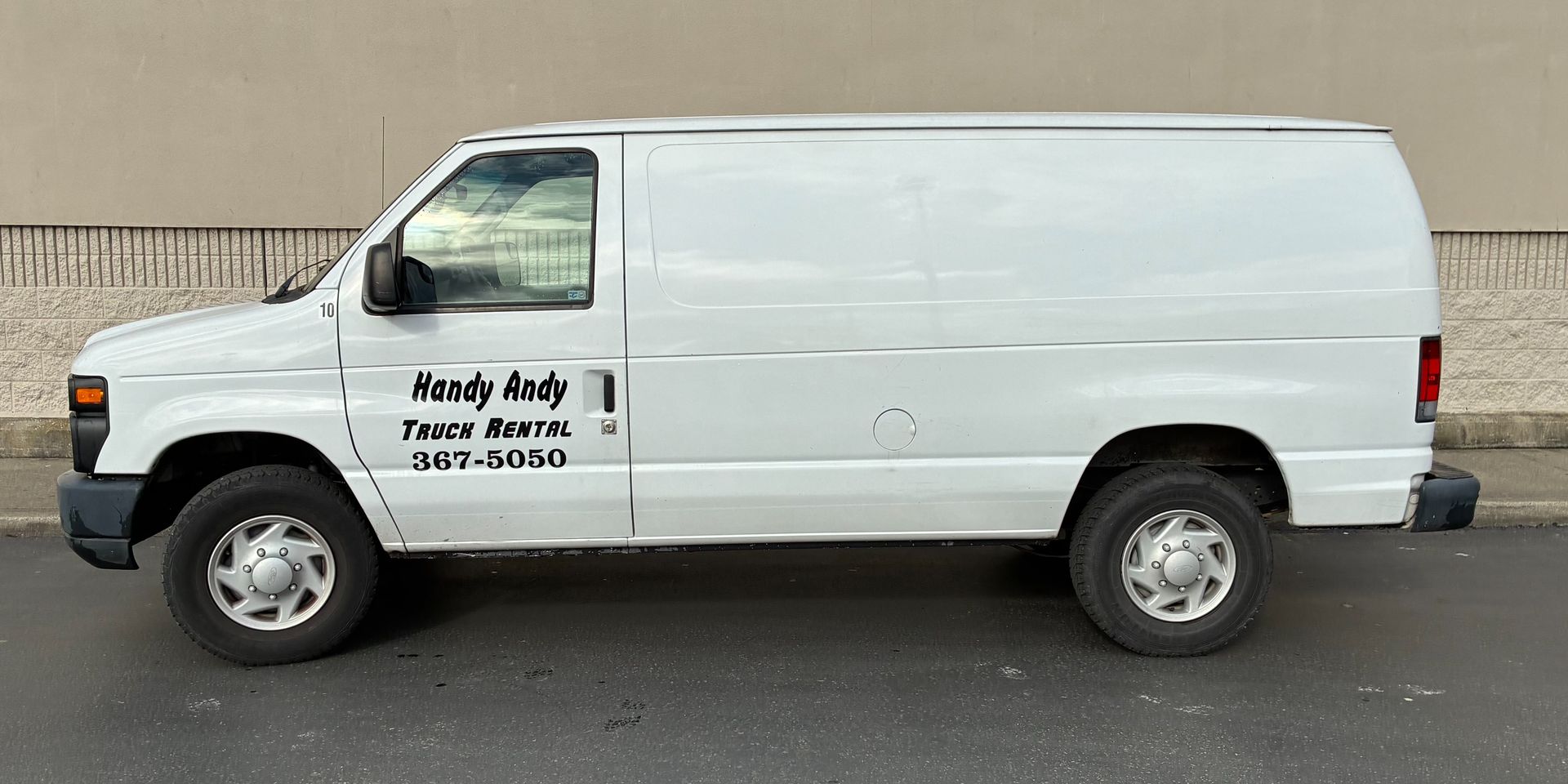 White cargo van with company lettering on the side, parked in profile on a street.