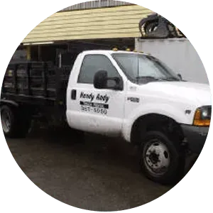 White flatbed truck with black bed, parked near a building.