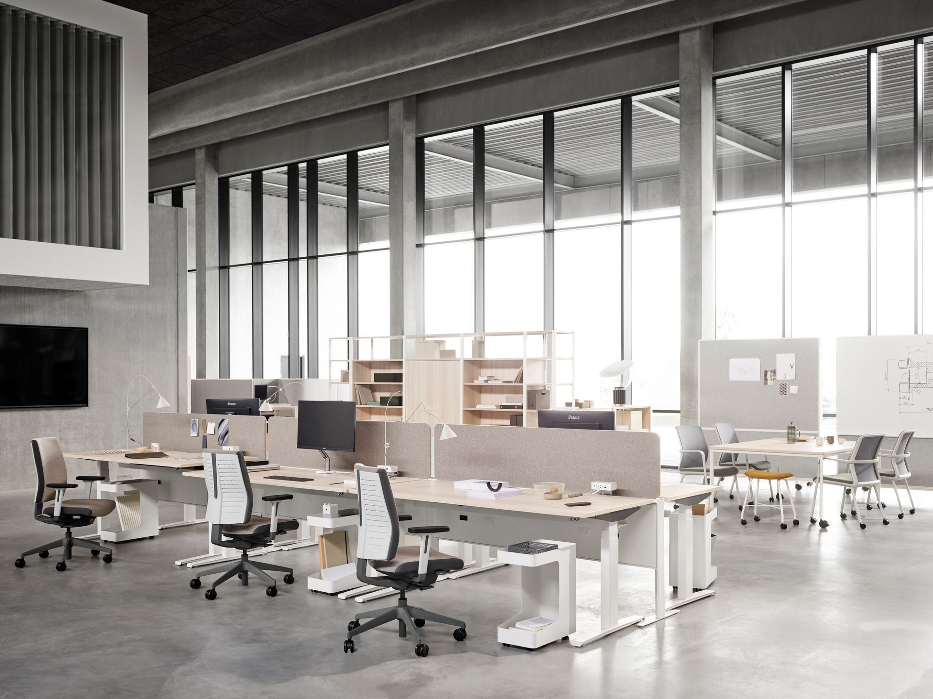 Modern office space with desks, chairs, computers, and large windows.  Neutral colors with a bright, open layout.