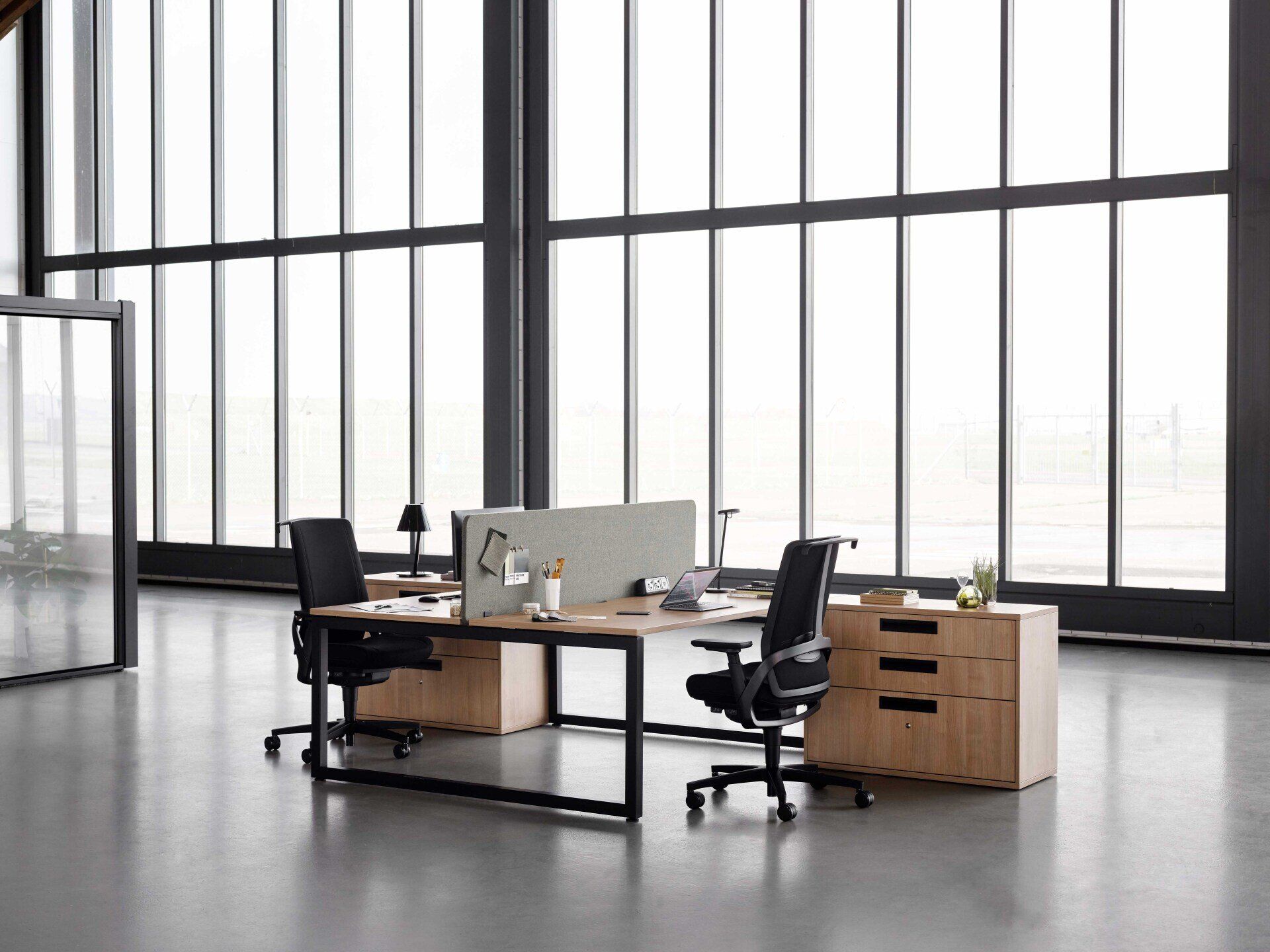 dual L-shape desks and tackboard dividers with black chairs