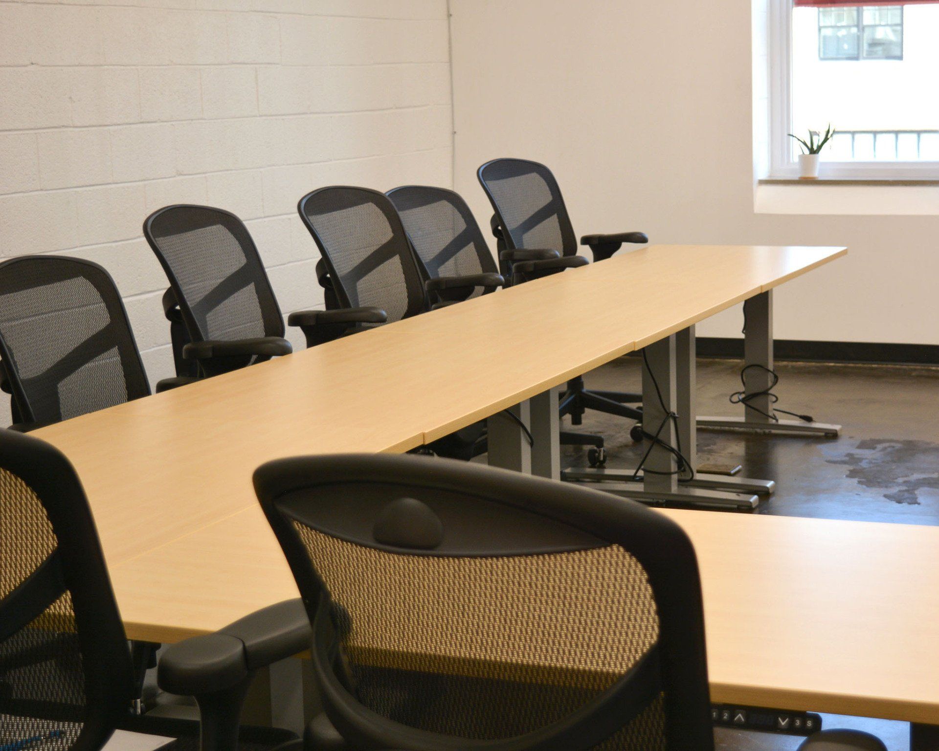 a row of chairs are lined up in front of a long wooden table