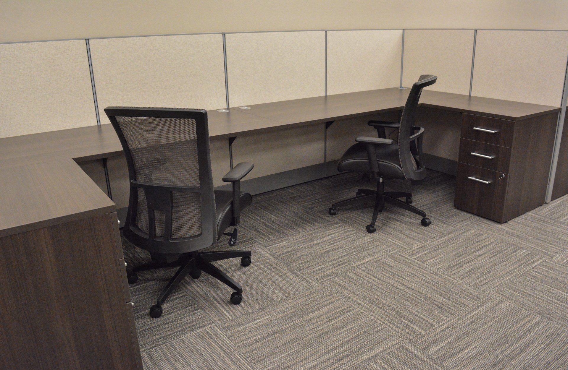 a cubicle with two chairs and side-by-side desks