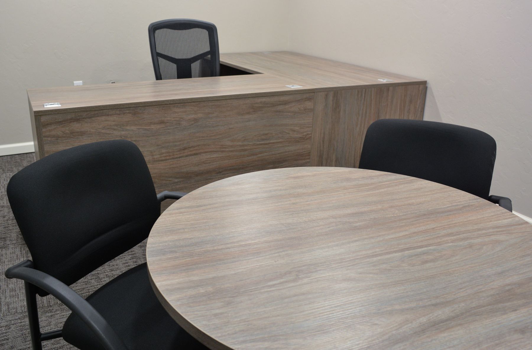 An office with a desk and a round table and chairs