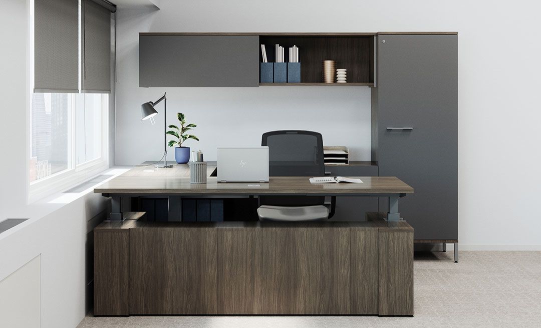 a laptop sits on an adjustable desk with storage behind