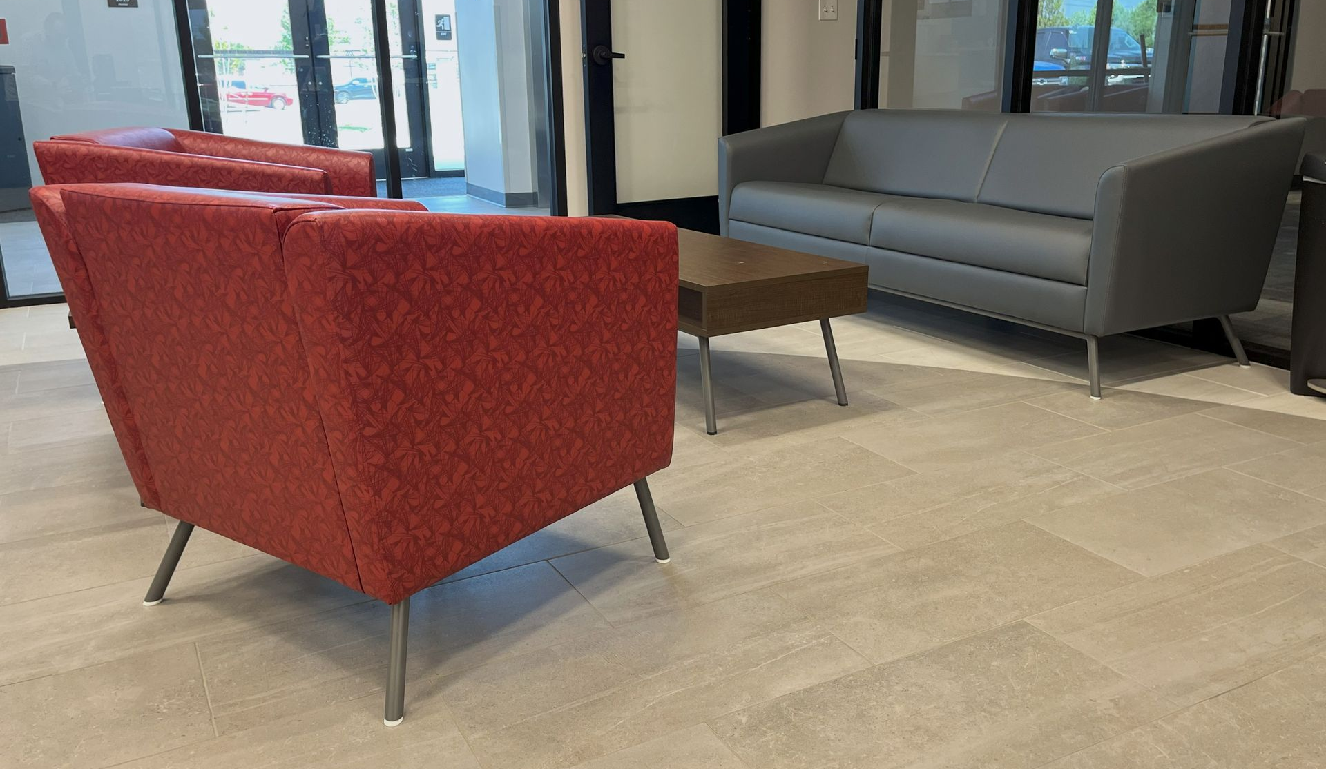 Red and gray seating area in a lobby: red armchairs, gray sofa, and a small coffee table.
