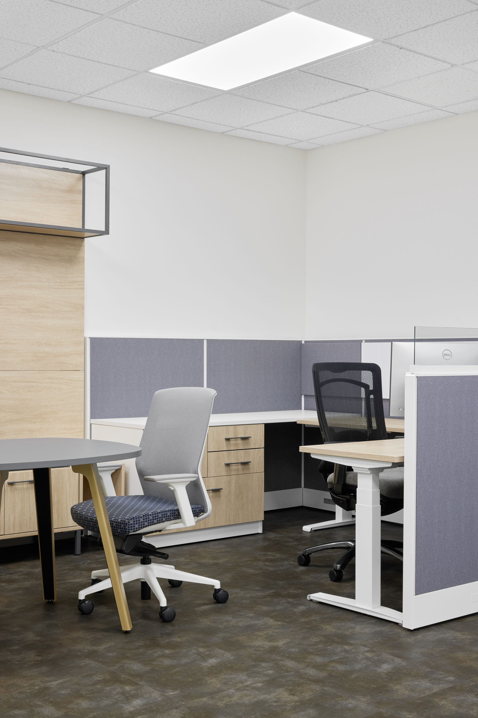 Gray meeting table with a desk chair next to a gray and white cubicle 