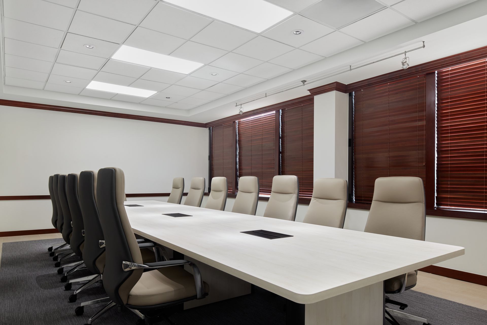 White boardroom table with taupe leather high back conference chairs.