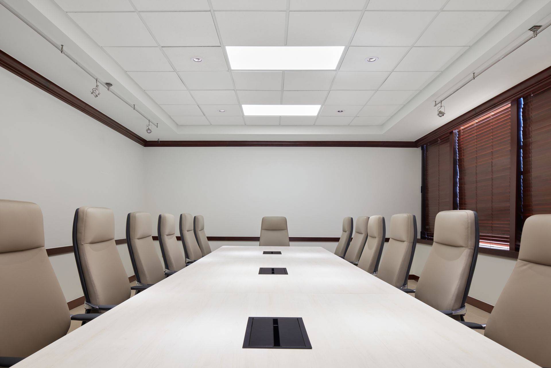 End view of boardroom table surrounded with taupe leather executive chairs.