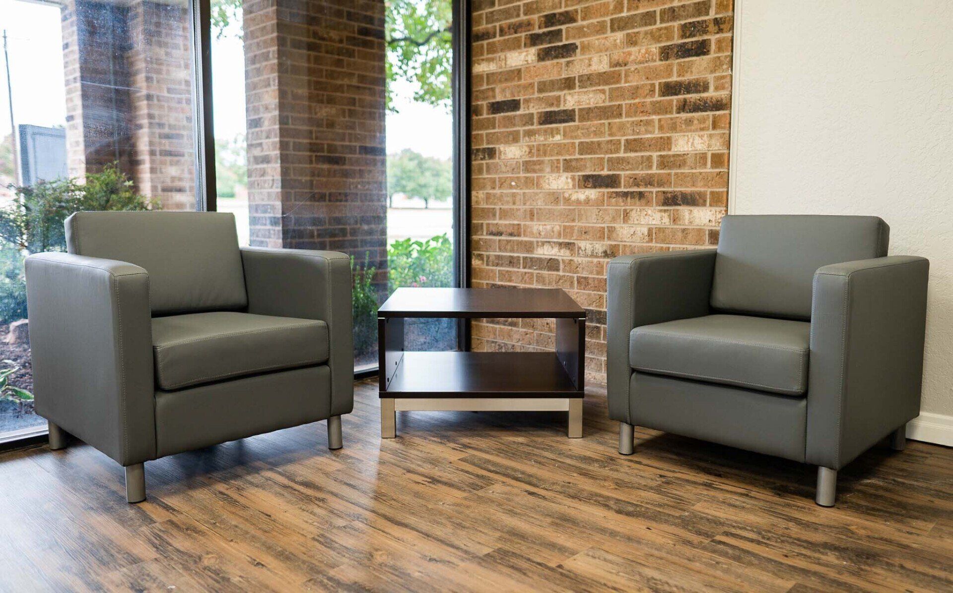 two chairs and a table in a room with a brick wall
