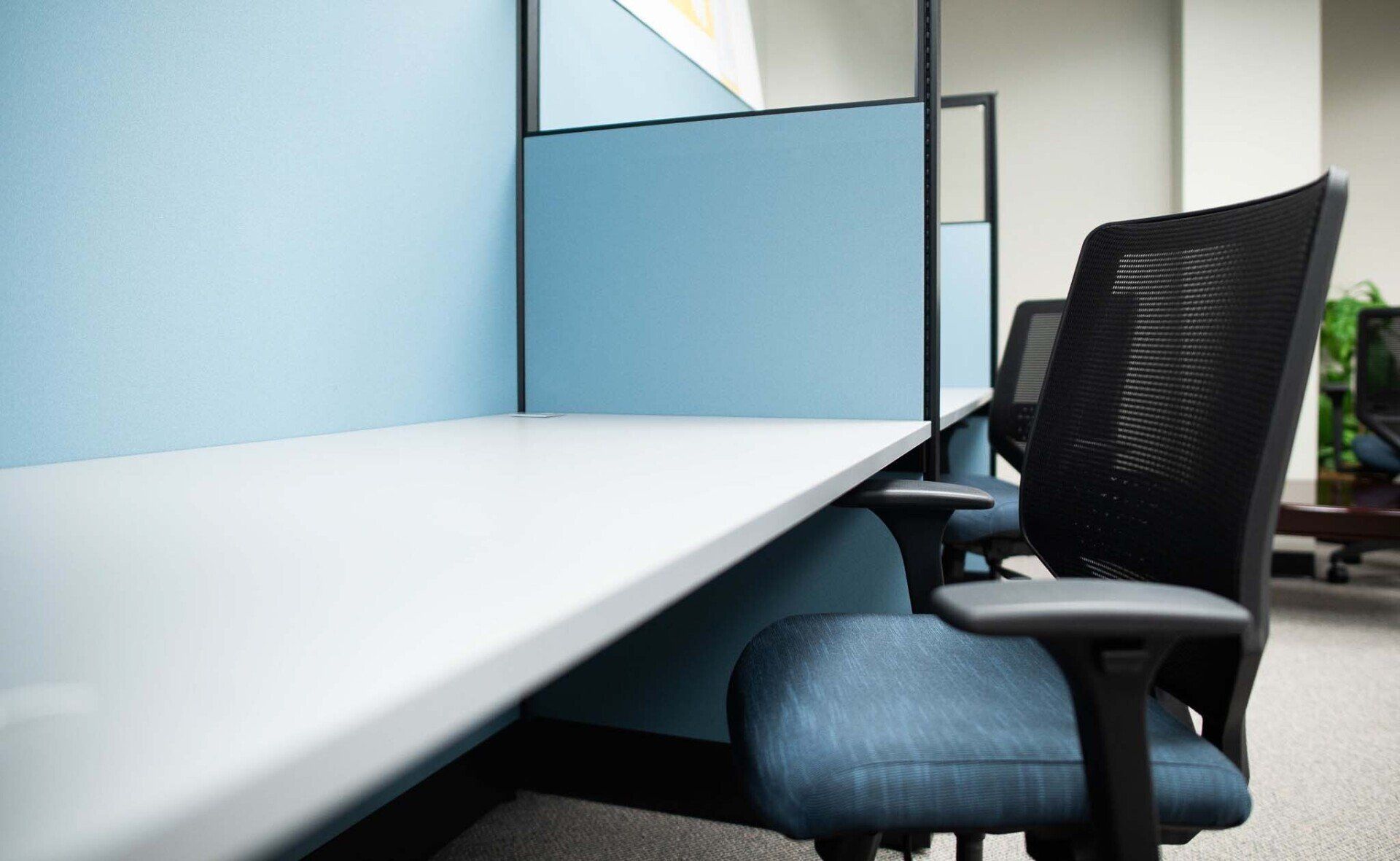 A chair is sitting in front of a desk in an office cubicle.