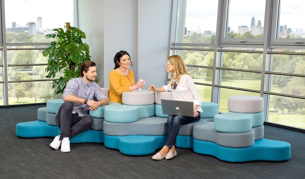 a man and two women sit and work on a blue modular seating unit