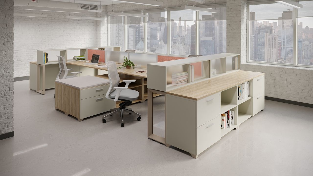 Modern office space with light wood and white furniture, desks, and storage. Window in background.