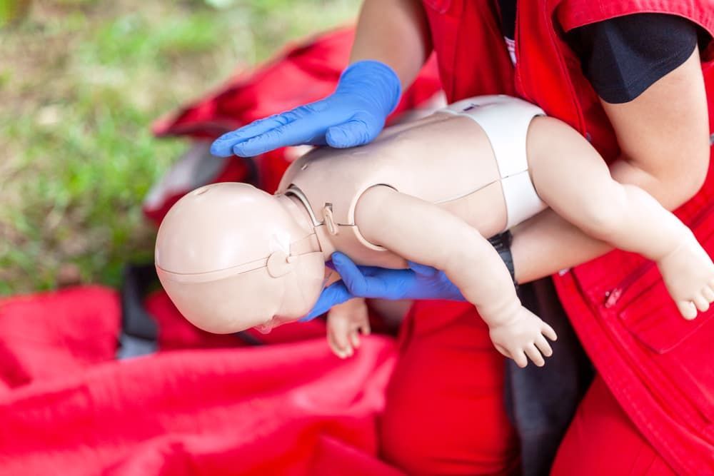 Gloved Person Performing CPR on a Training Mannequin on a Red Surface Outdoors — Revive Training in Alstonville, NSW