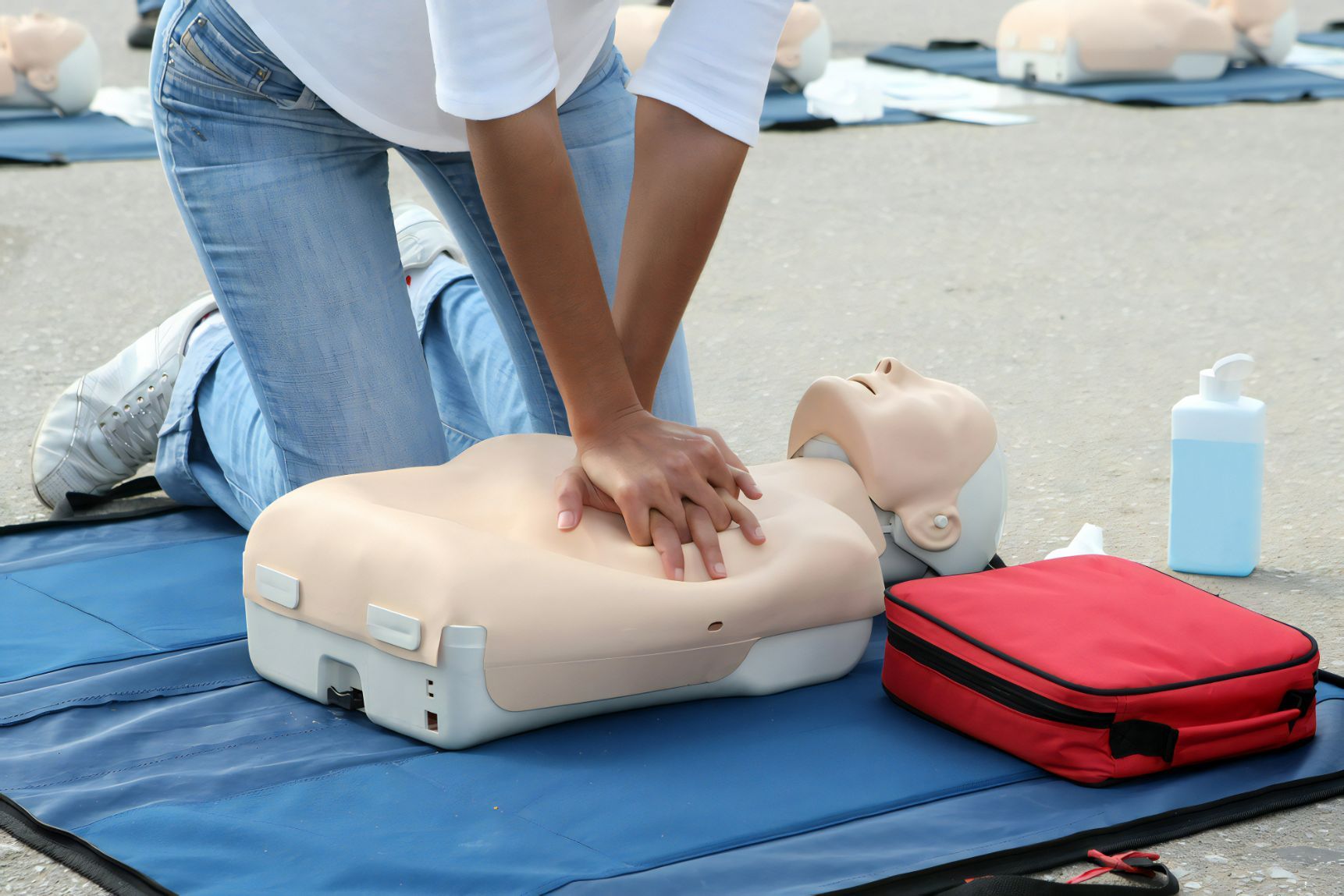 Person Performing CPR on a Training Mannequin Beside a Red First Aid Kit — Revive Training in Alstonville, NSW