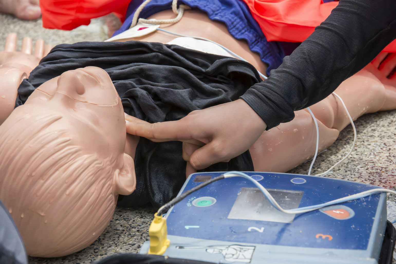 CPR Training Mannequin on the Ground With a Hand Pressing Its Chest — Revive Training in Alstonville, NSW