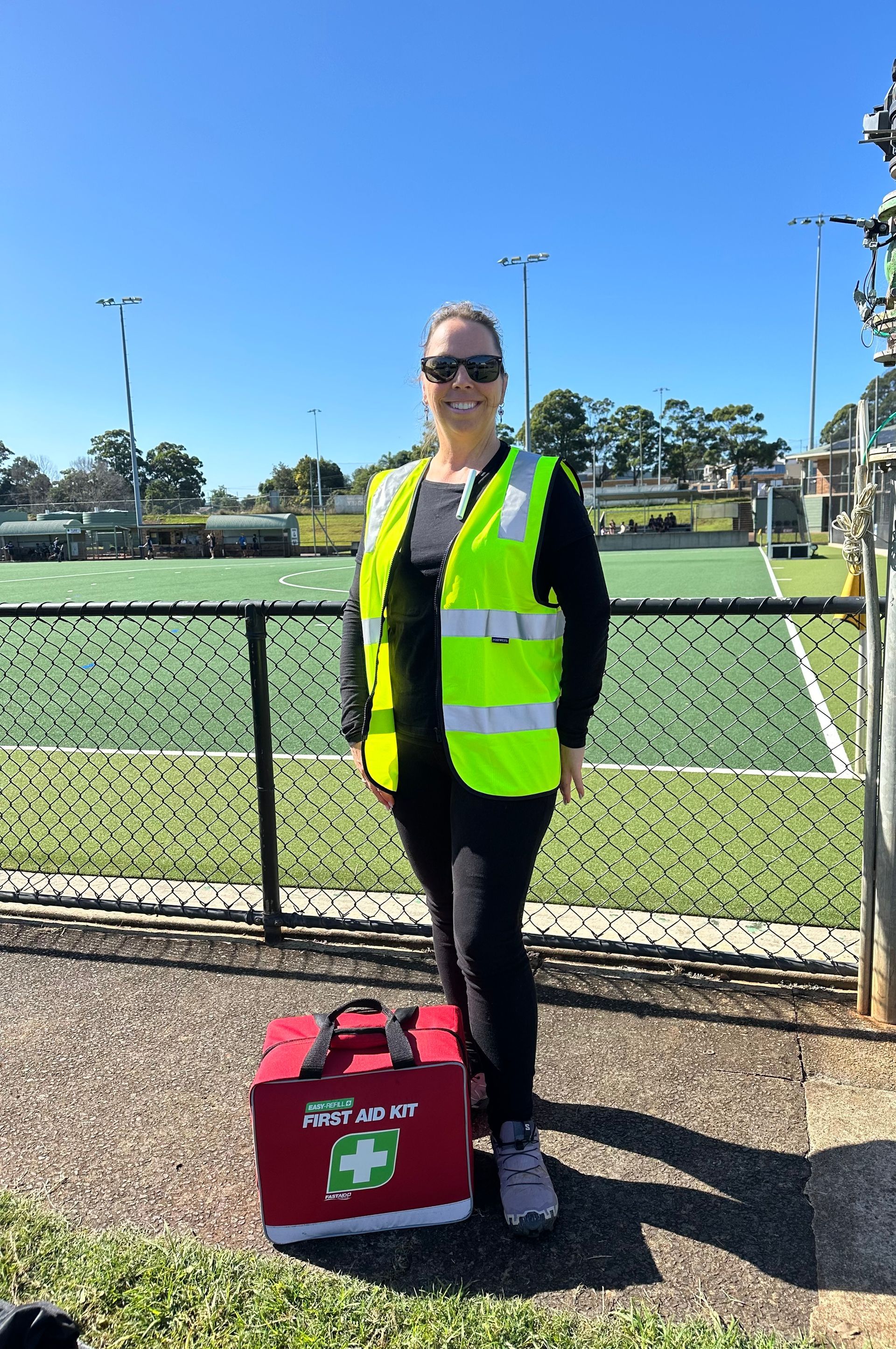 Person in a Safety Vest Standing by a Sports Field With a First Aid Bag — Revive Training in Alstonville, NSW