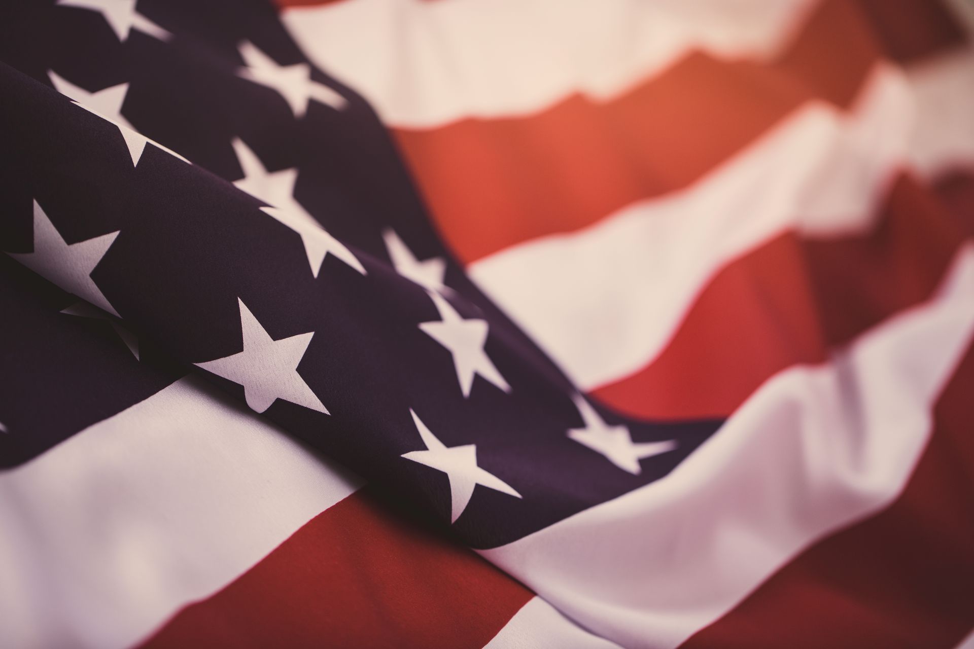 A man in white gloves is holding an american flag in front of a woman.