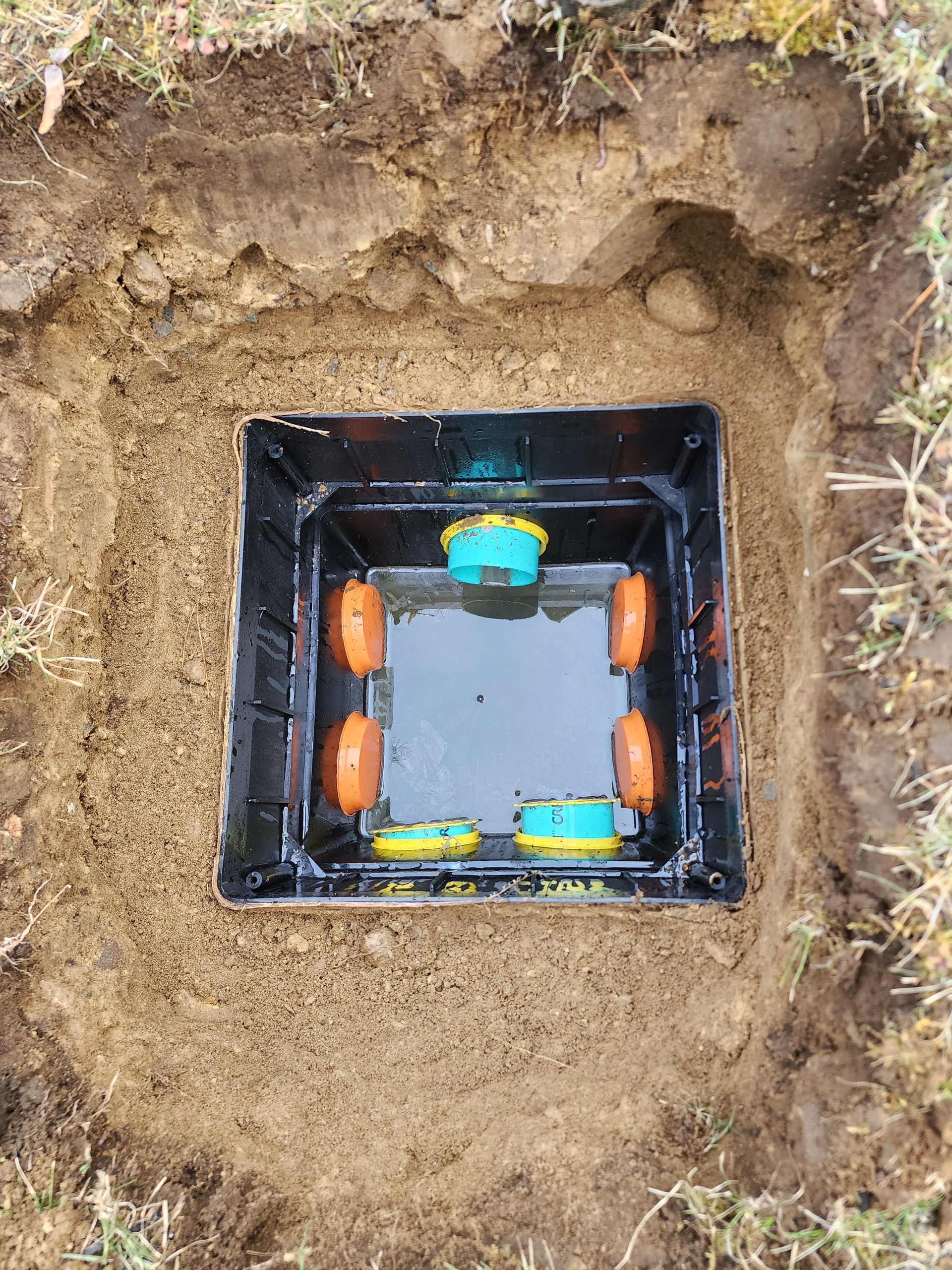 Open ground box with orange and teal sensors set in soil
