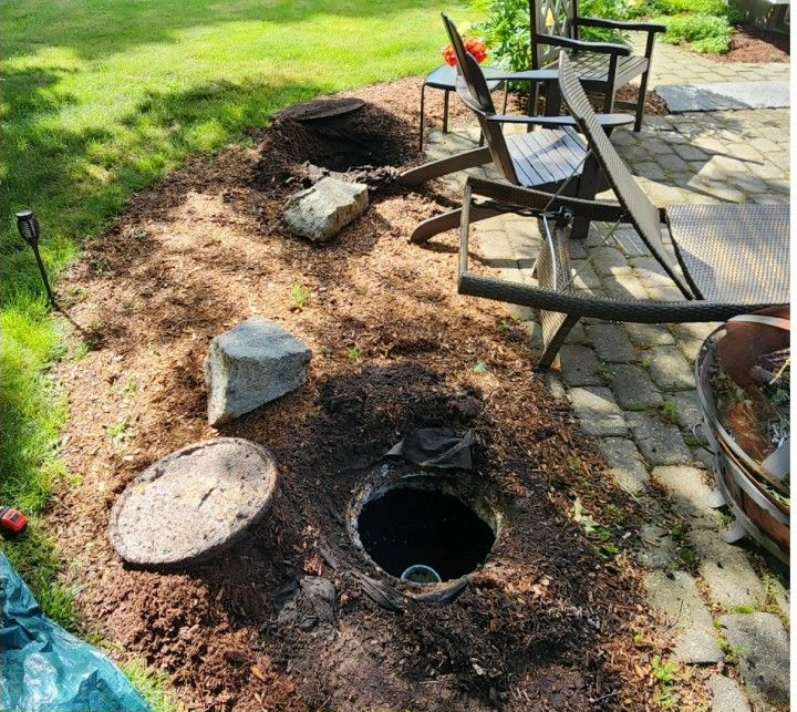 Backyard fire pit area with chairs, stone walkway, and mulch border