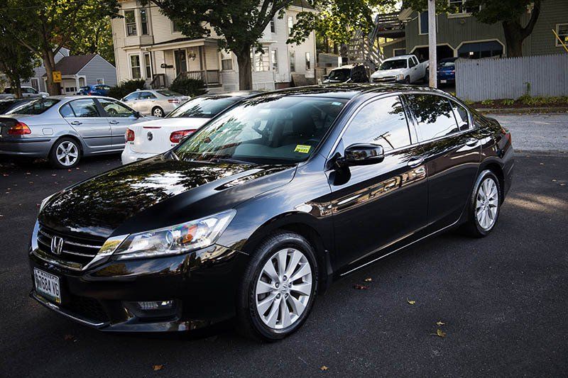 Black Honda Accord sedan parked on a paved surface with other vehicles in a parking lot.
