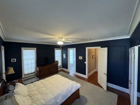 Bedroom with navy walls, white trim, wood furniture, and carpeted floor
