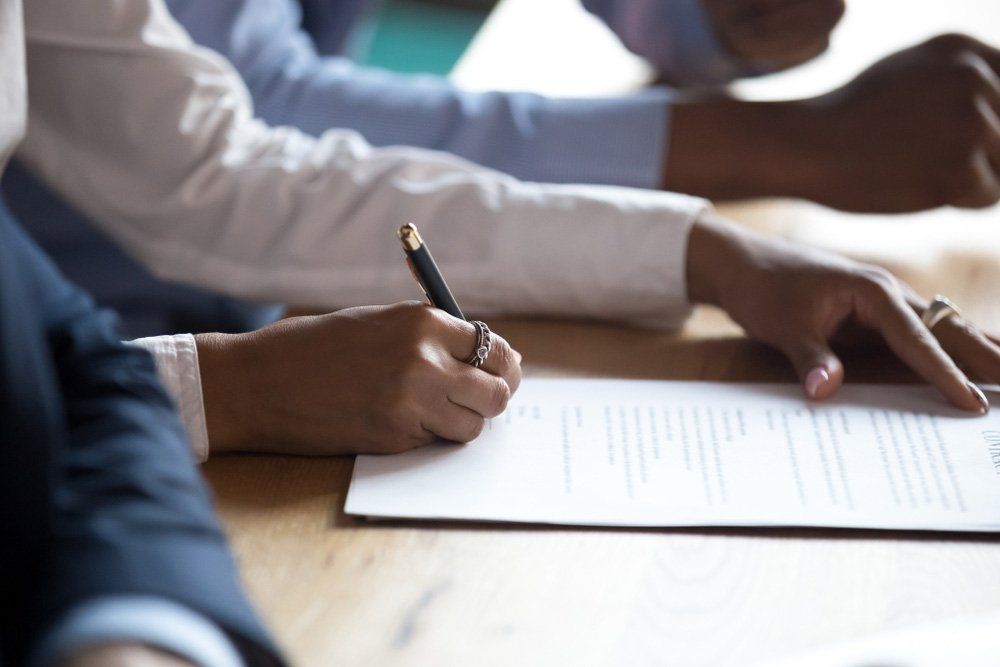 Woman Hands Signing Contract — Commercial Property Law in Gladstone, QLD