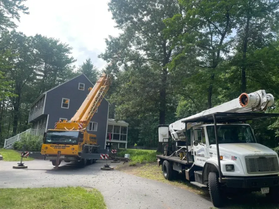 A truck with a crane on top of it is parked in front of a house.