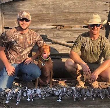Two men and a dog are posing for a picture.