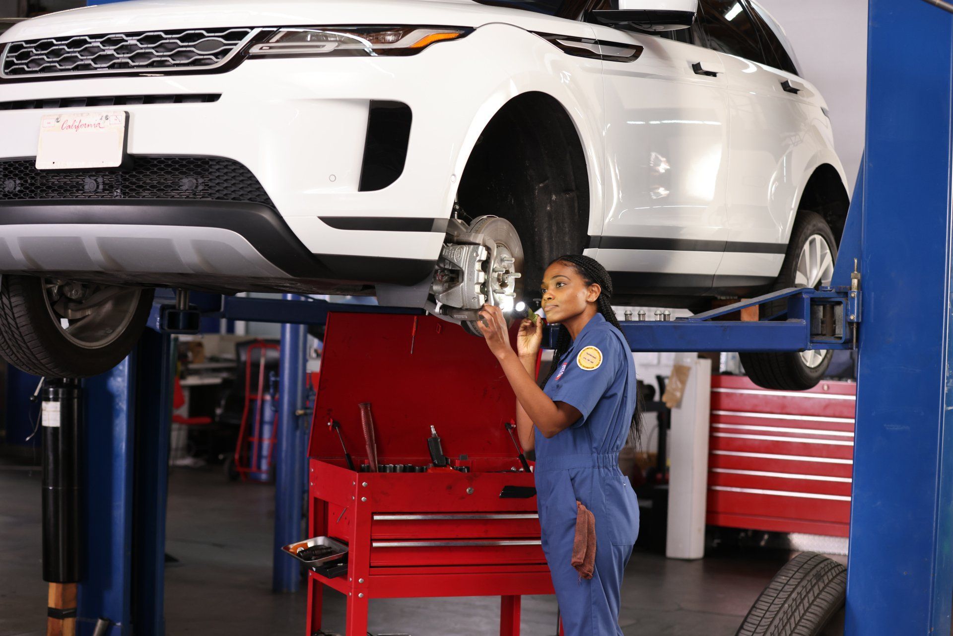Mechanic inspecting a white SUV on a lift in an auto repair shop