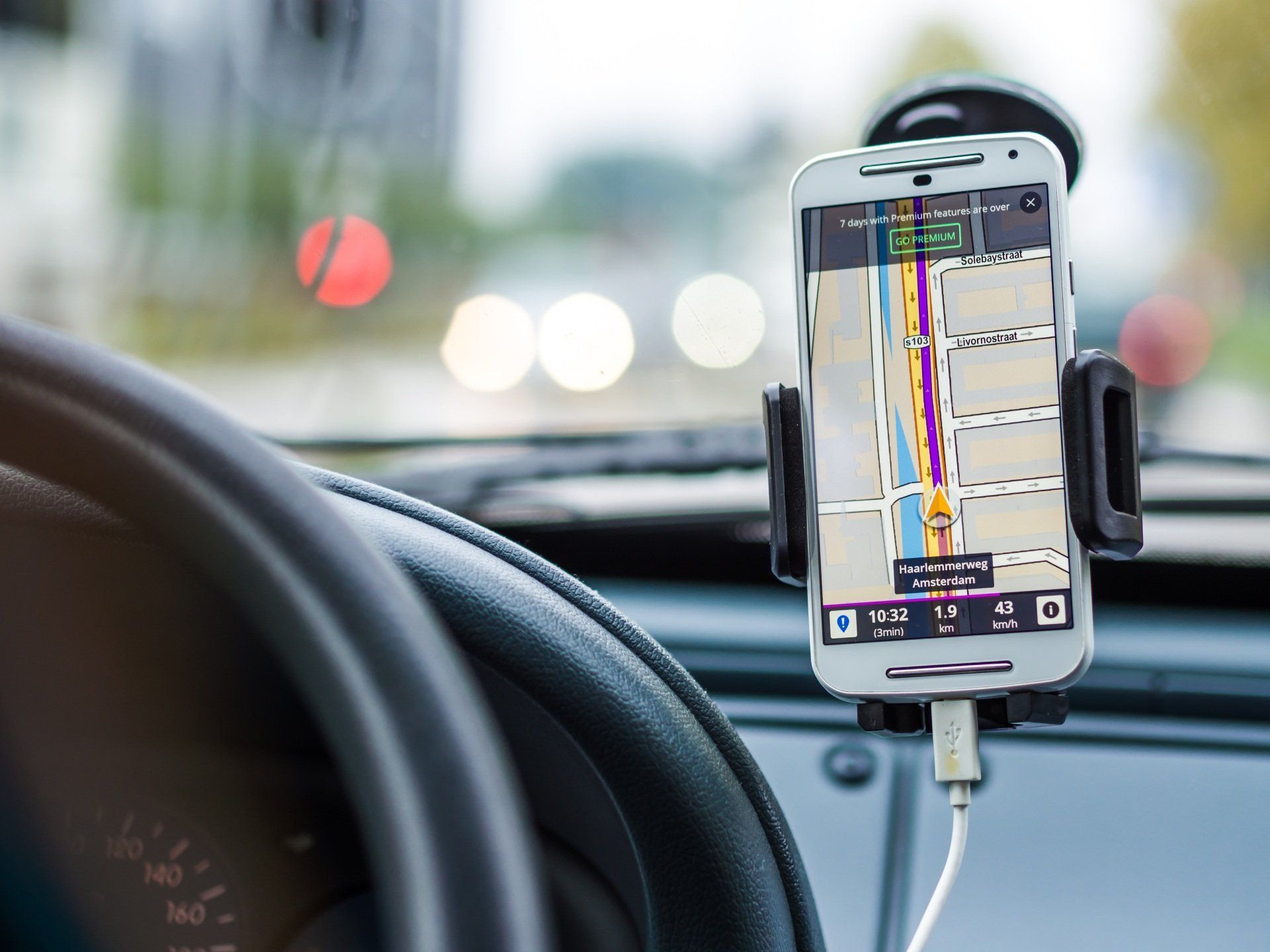 Smartphone mounted on a car dashboard showing a navigation map while driving.