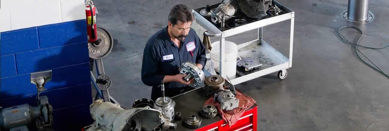 Mechanic working on a motorcycle in a workshop with tools and a red engine stand