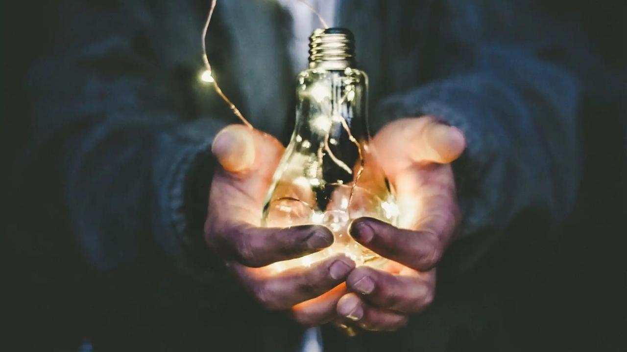 A person is holding a light bulb in their hands.