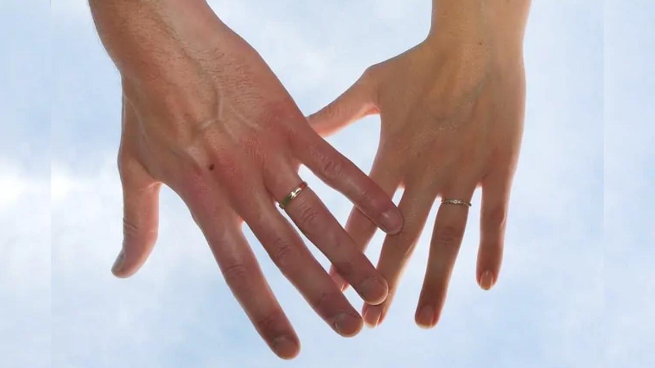 A man and woman holding hands with wedding rings on their fingers