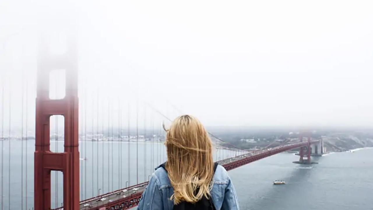 A woman is standing on top of a bridge overlooking a body of water.