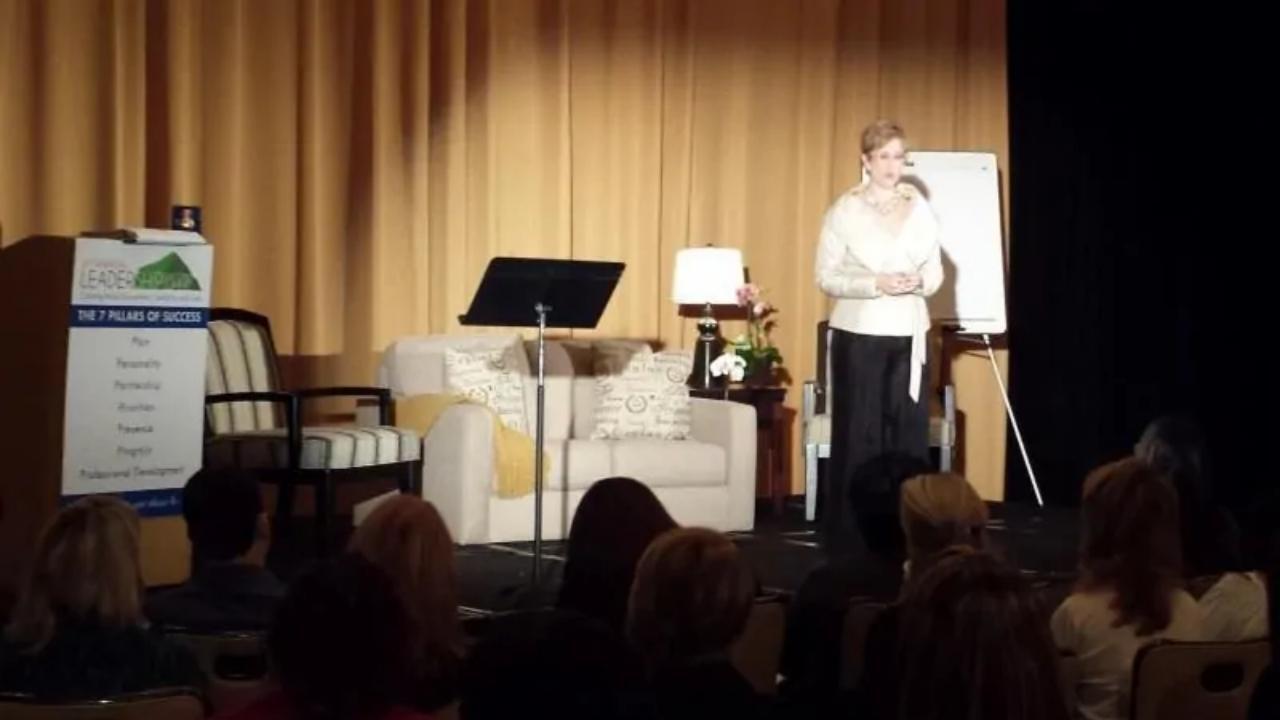 A woman is standing on a stage speaking into a microphone