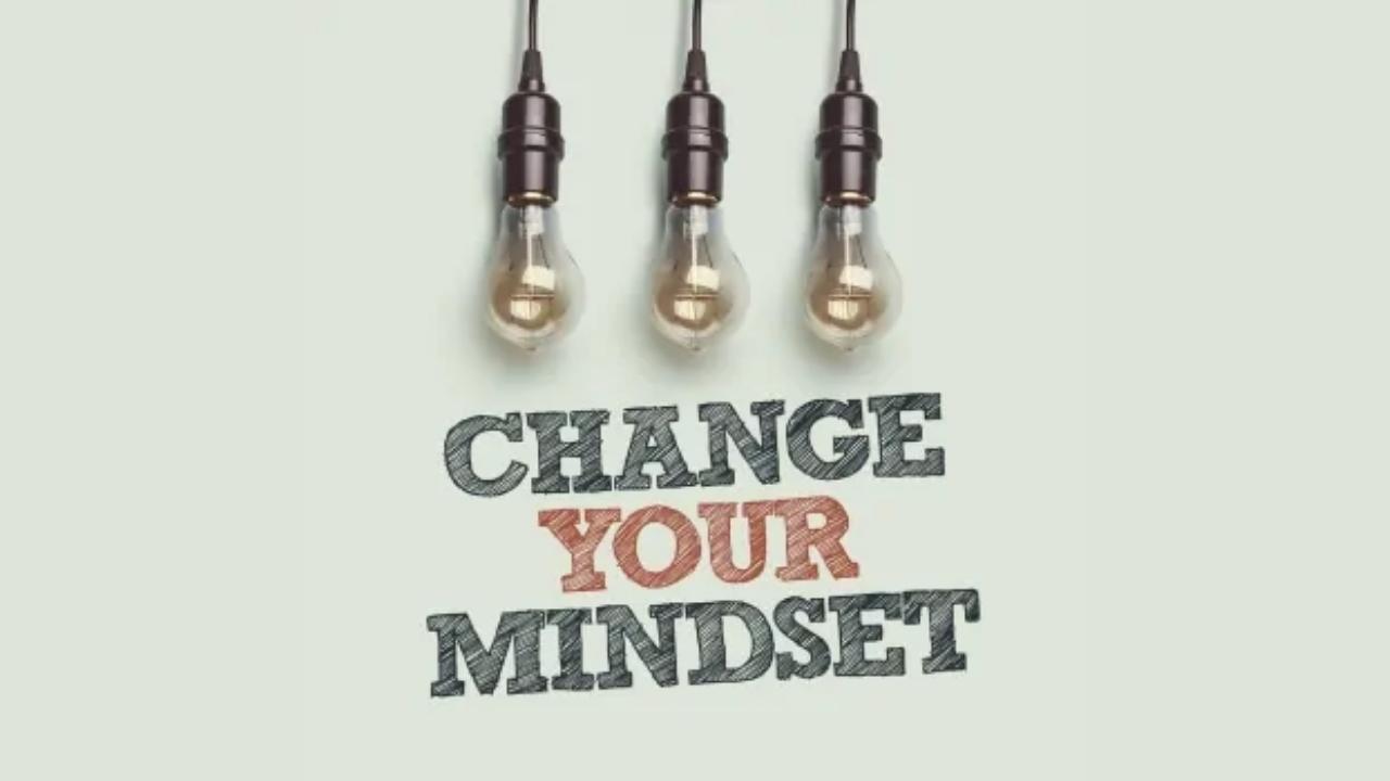 A sign that says `` change your mindset '' with three light bulbs hanging from the ceiling.